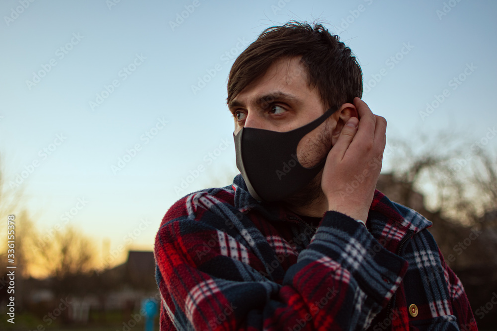 Portrait of a guy in a black mask on a background of a sunset sky on a city street. Protective, medical mask against viruses, germs. illness, infection. Quarantine Covid 19. Health safety concept
Portrait of a guy in a black mask on a background of a sunset sky on a city street. Protective, medical mask against viruses, germs. illness, infection. Quarantine Covid 19. Health safety concept