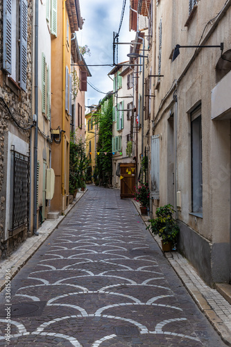 Fototapeta Naklejka Na Ścianę i Meble -  Empty uphill street with cobblestones in Antibes, France 
