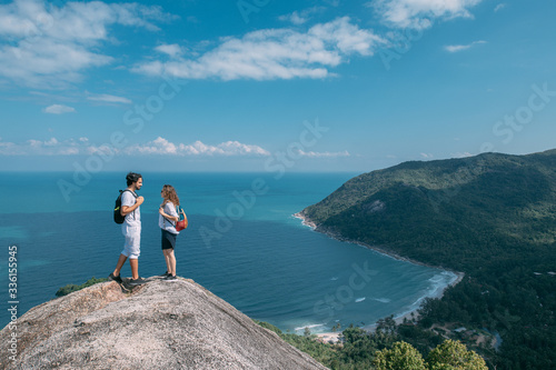 A couple stand on a rock at a viewpoint with an epic view of the ocean