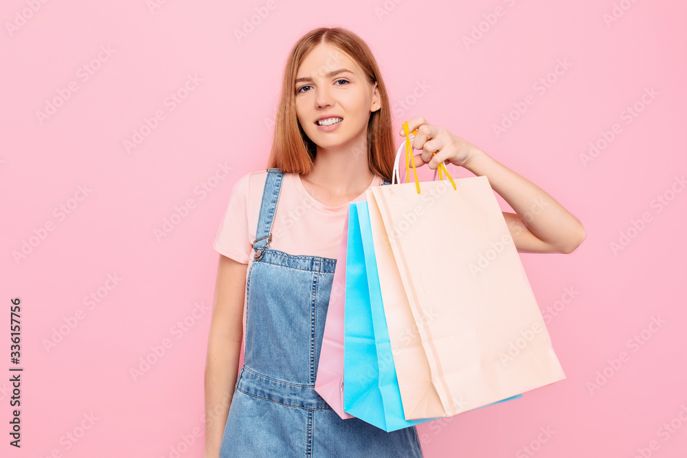 young stylish girl shopper holds shopping bags after shopping on an isolated pink background young stylish girl shopper holds shopping bags after shopping on an isolated pink background