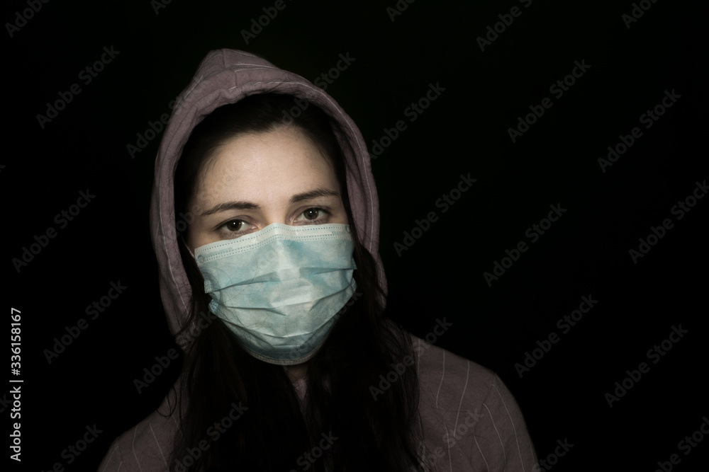 Young beautiful girl infected with coronavirus in a medical mask on a dark background Young beautiful girl infected with coronavirus in a medical mask on a dark background