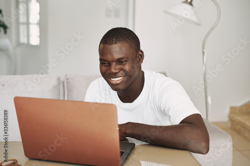 A man of African appearance at home in front of a laptop relaxing