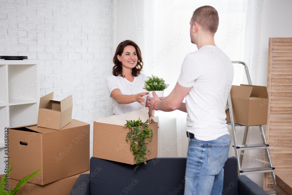 moving day concept - happy young couple unpacking cardboard boxes at new home moving day concept - happy young couple unpacking cardboard boxes at new home