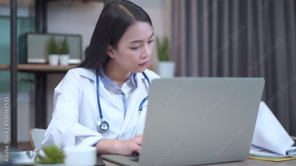 Asian female doctor working about document with computer and memo record at hospital office Asian female doctor working about document with computer and memo record at hospital office