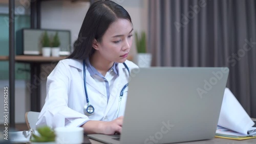 Asian female doctor working about document with computer and memo record at hospital office