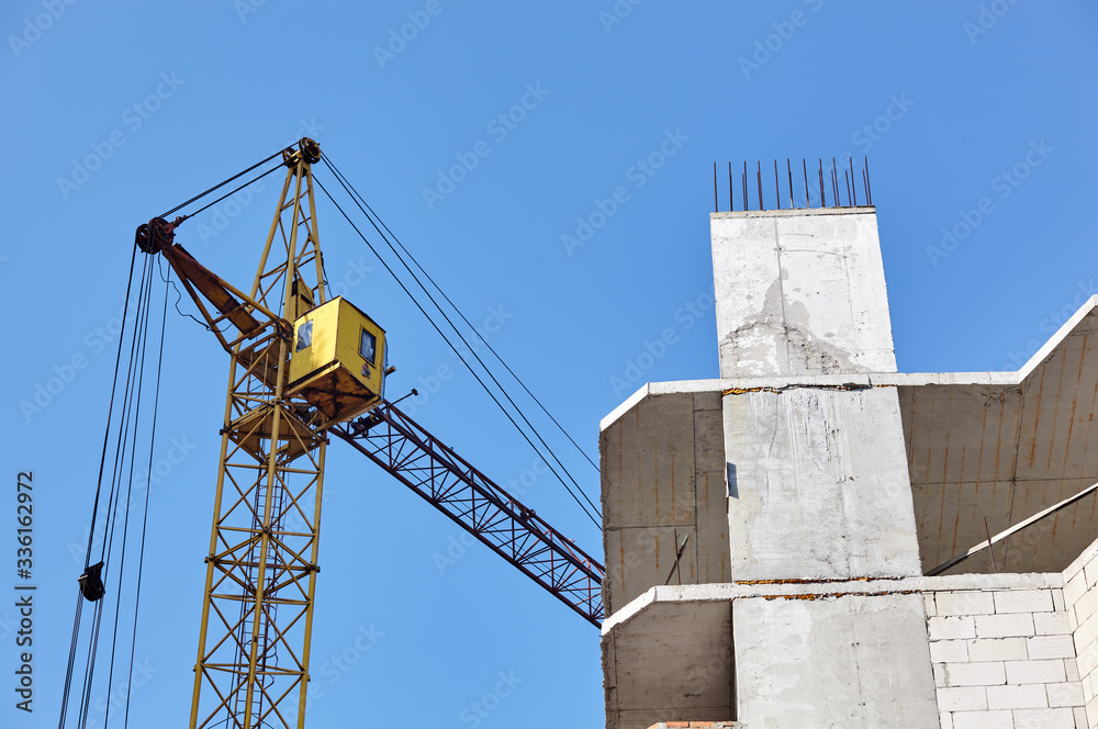 Tower crane building a house. Concrete building under construction. Construction site