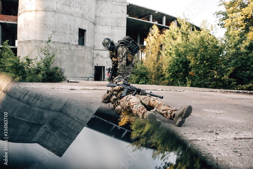 Принти на полотні Military soldier drags teammate wounded from bullets by the scruff of the ground