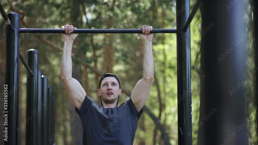 Adult caucasian strong athlete is doing a pull up exercise on a crossbar at the gym at the park during daily workout, frontal shot Adult caucasian strong athlete is doing a pull up exercise on a crossbar at the gym at the park during daily workout, frontal shot