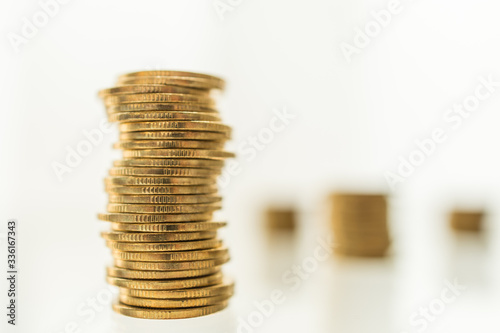 Business, Money, Finance, Security and Saving Concept. Close up of unstable stack of gold coins on table with green nature and copy space.