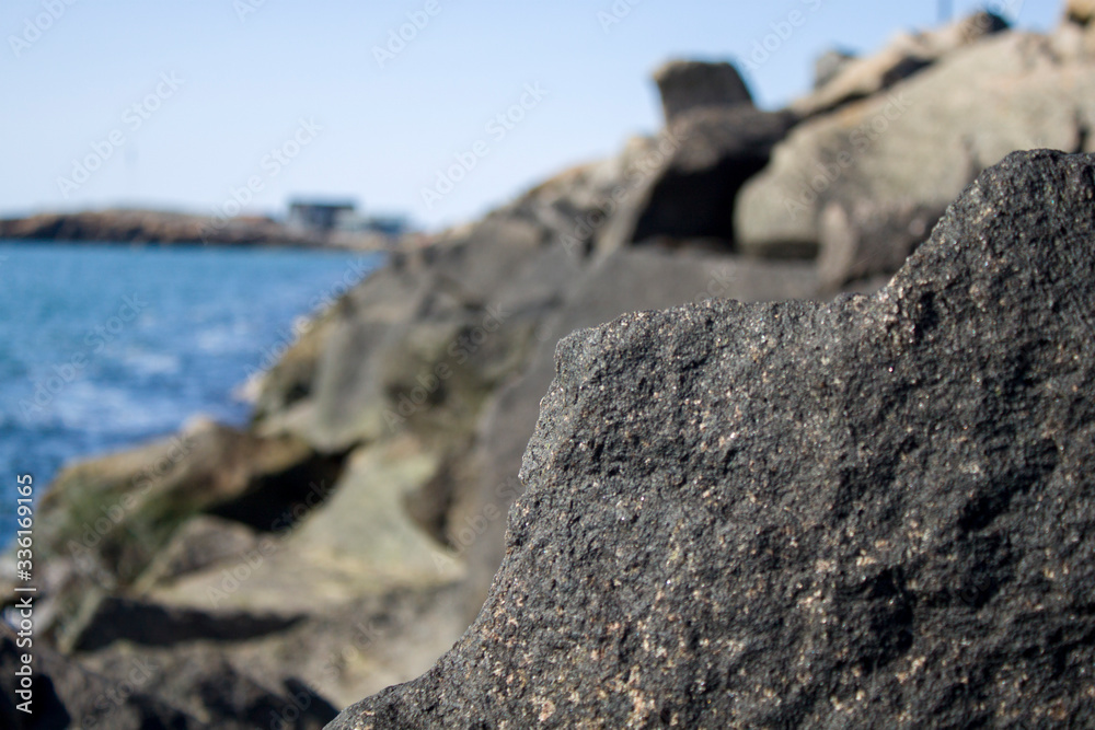 A beach with many stones and rocks in and near the blue water