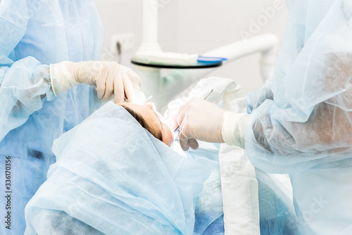 Close-up of the hands of a dentist and nurse surgeon over an operating room during a dental implant operation photo