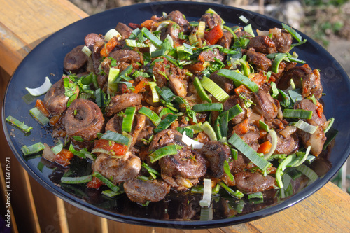 fried chicken hearts with green onions on a large black plate