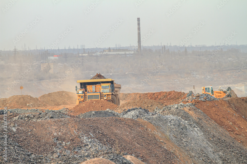 A large mining truck dumps waste rock to a dump A large mining truck dumps waste rock to a dump