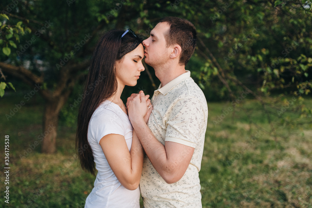 Lovers, beautiful, stylish guy and a girl in tracksuits hug in the forest, outdoors in a green garden. Love story newlyweds. Photography, concept. Lovers, beautiful, stylish guy and a girl in tracksuits hug in the forest, outdoors in a green garden. Love story newlyweds. Photography, concept.