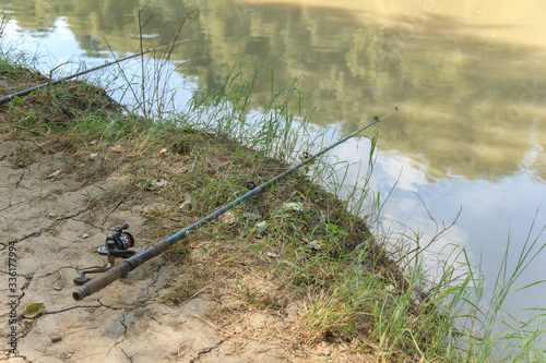 two fishing rods on the river bank with muddy water