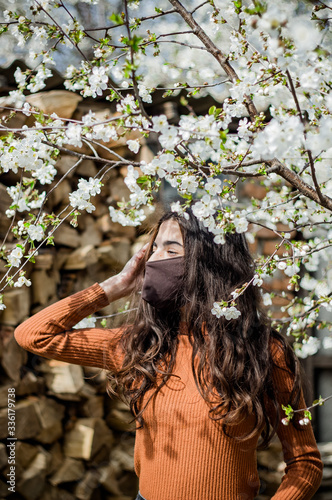 Girl looks in a mask respiratory at a tree with flowers