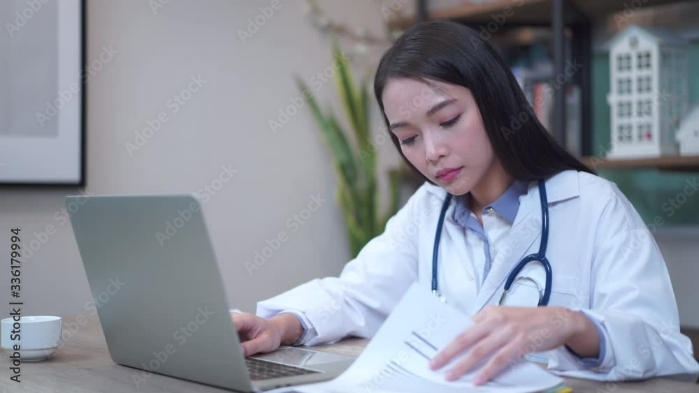 Asian female doctor working about document with computer at hospital office Asian female doctor working about document with computer at hospital office
