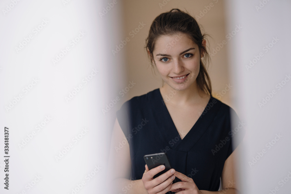 Portrait of smiling young woman with mobile phone