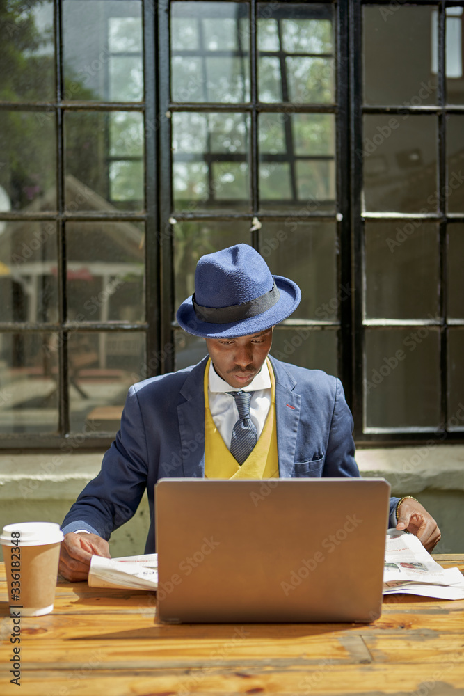Young businessman wearing old-fashioned suit and hat reading newspaper at an outdoor cafe Young businessman wearing old-fashioned suit and hat reading newspaper at an outdoor cafe