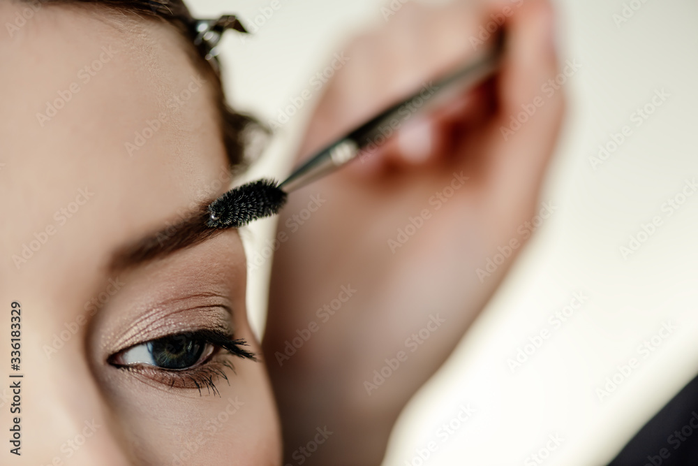 cropped view of makeup artist styling eyebrow of woman