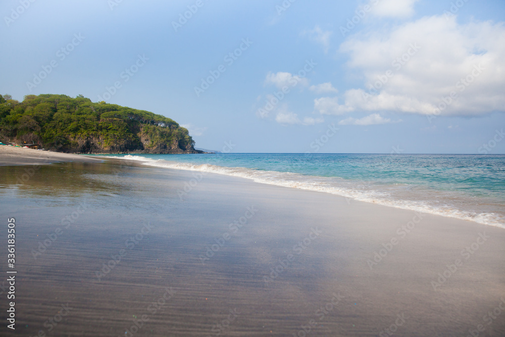 Beach and wave of blue ocean on sand summer background. Waves on the sandy beach.