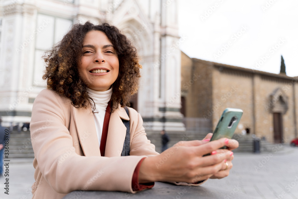 Smiling woman with smartphone at Santa Croce church, Florence, Italy Smiling woman with smartphone at Santa Croce church, Florence, Italy
