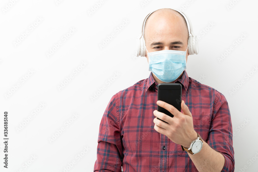 Man with mask and headphones looking at phone Man with mask and headphones looking at phone