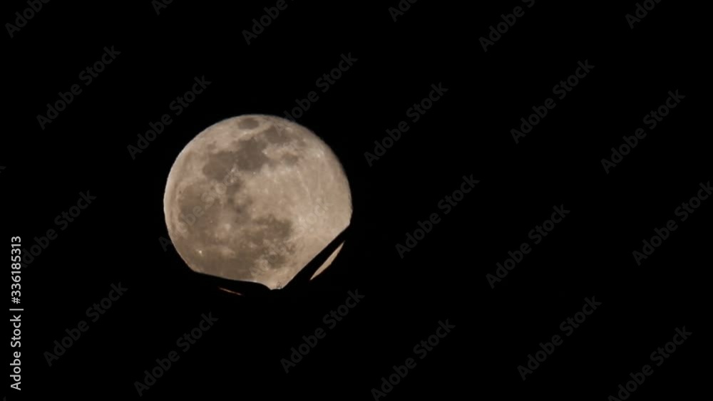 The full moon moves against the black night sky. The blades of a windmill move against the backdrop of a full moon. The full moon moves against the black night sky. The blades of a windmill move against the backdrop of a full moon.