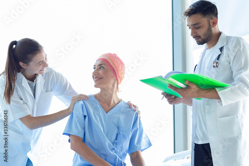 Professional doctor and nurse happy to take care a smiling female patient. Senior Caucasian woman cover head with a cloth caused of chemotherapy cancer.