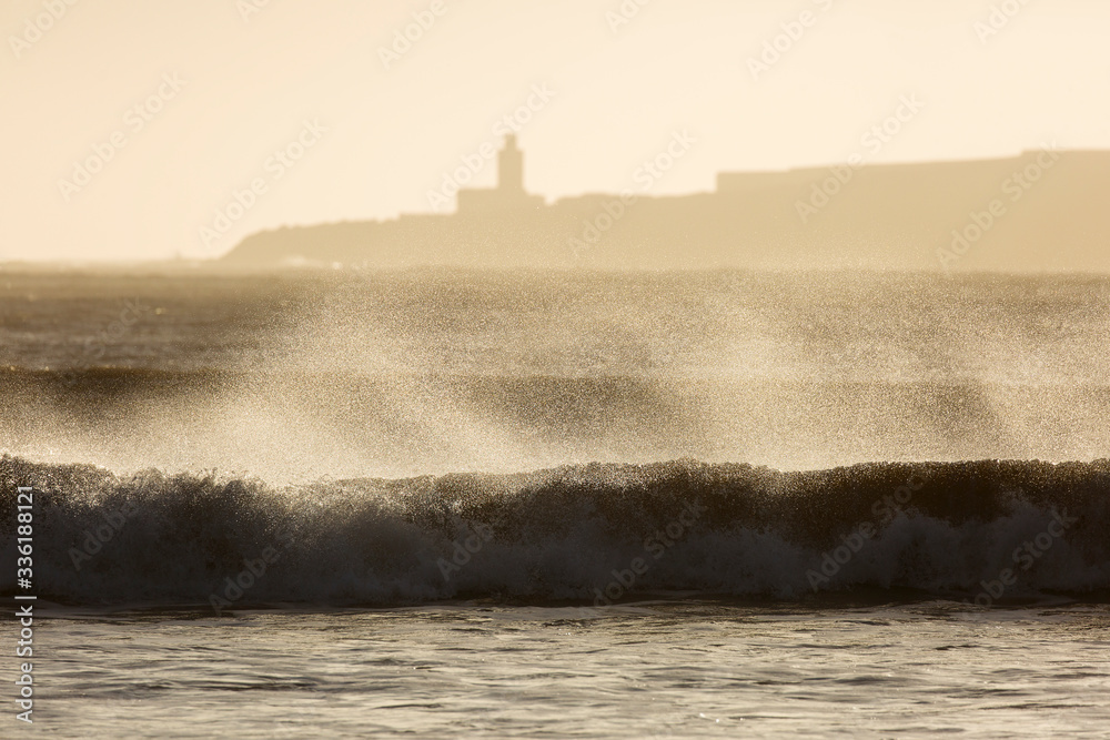 Big waves of ocean in Essaouira with Mosque in background. Morocco