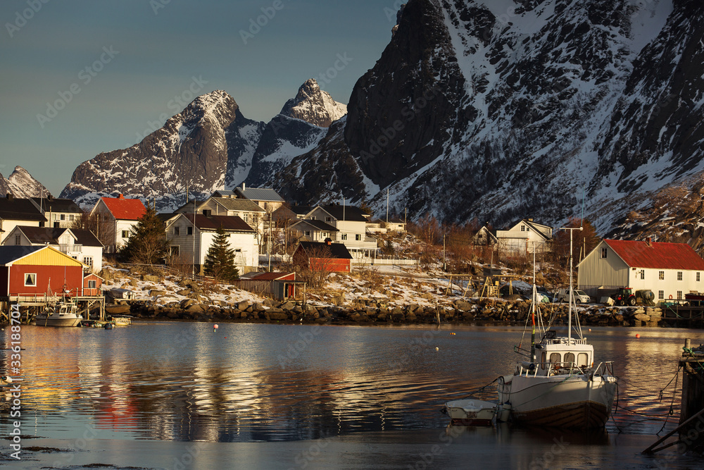 View of beautiful Sacrisoya village in winter time with montains in background with light of sunrise. Lofoten, Norway.