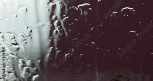 Raindrops hitting a window pane on a rainy dreary day.