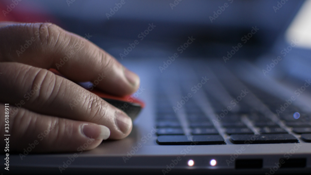 Man's hand with a wireless mouse on a laptop