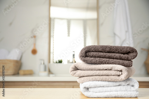 Fresh towels on wooden table in bathroom. Space for text photo