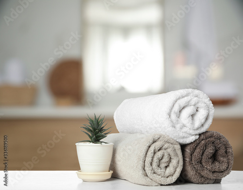 Fresh towels and houseplant on white table in bathroom. Space for text