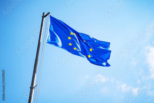 EU flag fluttering with the wind on the blue sky.