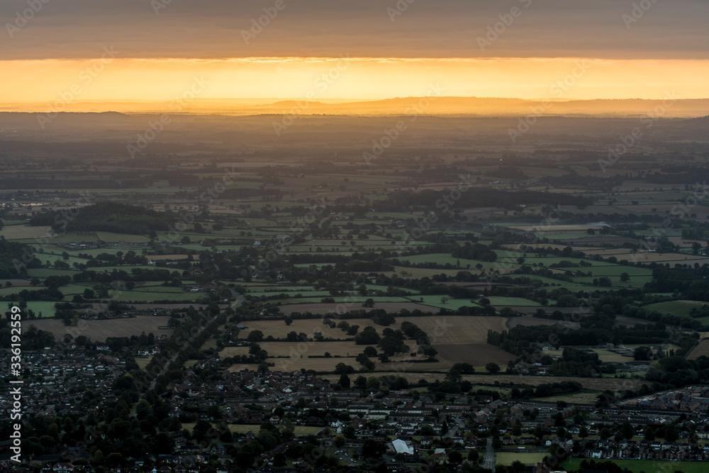 Fototapeta premium Sun rising on an early, cold winter morning over the West Midlands countryside. Light breaking through the early morning mist/fog in the distance