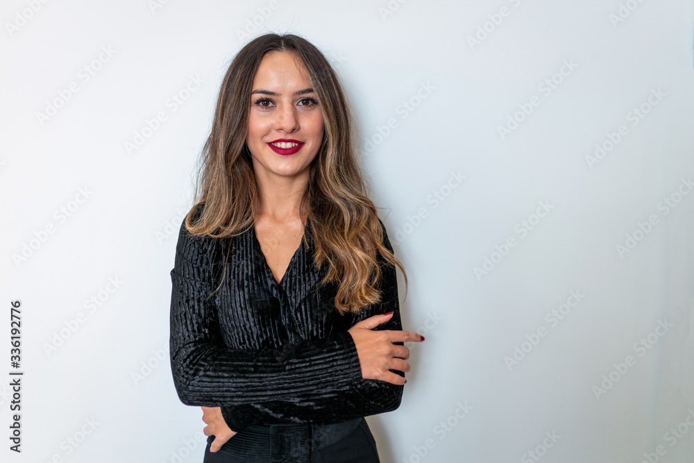 A smiling professional female executive stares forward with her standing arms tied. A smiling professional female executive stares forward with her standing arms tied.