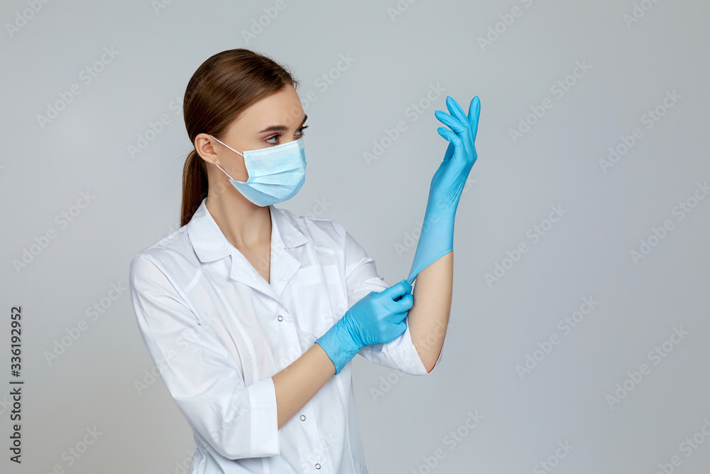 woman doctor in white uniform wearing mask and rubber gloves on gray background. copy space woman doctor in white uniform wearing mask and rubber gloves on gray background. copy space
