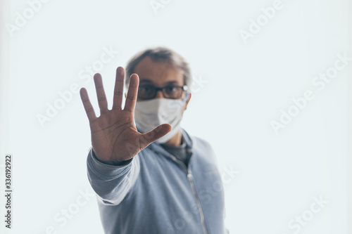 Man with medical mask showing stop gesture