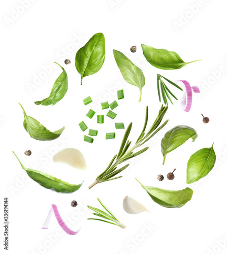 Basil leaves and other ingredients falling on white background