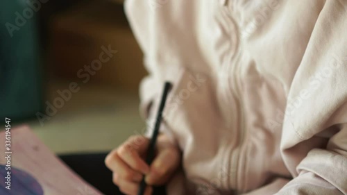 Sad drawing of a teenager, portrait of a girl with tears. A schoolgirl draws with crayons in a sketchbox while sitting on the floor in her room photo