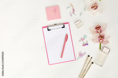 Mockup with clipboard, orchid flowers and clips. feminine office table. Flat lay, top view.