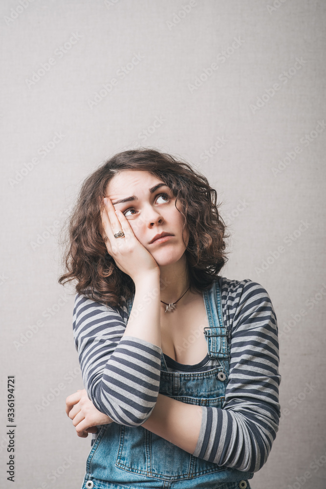 A woman looking up, thinking. Gray background A woman looking up, thinking. Gray background