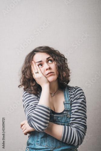 A woman looking up, thinking. Gray background