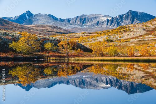 Mountain reflection on calm lake at autumn, Norway.