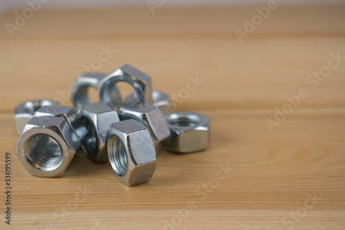 Metalowe nakrętki ułożone na drewnianej desce