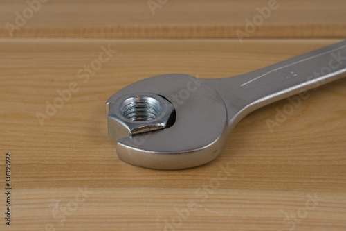 Metalowa nakrętka oraz klucz ułożone na drewnianej desce