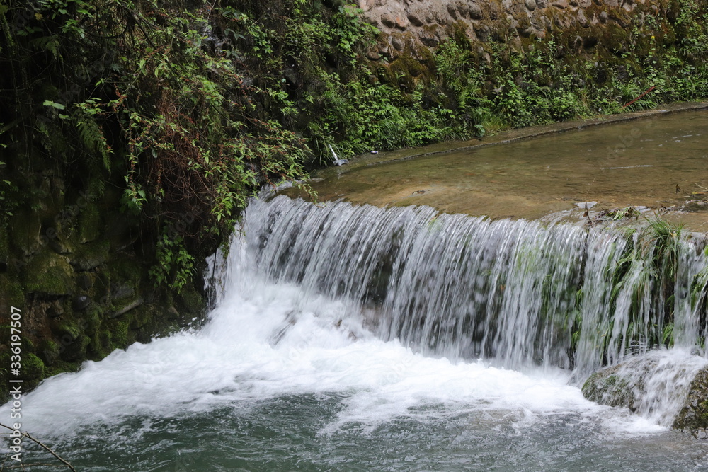 Beautiful landscape of cascade falls over mossy rocks, stones cover with moss, in a Mountain in Sichuan, China Beautiful landscape of cascade falls over mossy rocks, stones cover with moss, in a Mountain in Sichuan, China