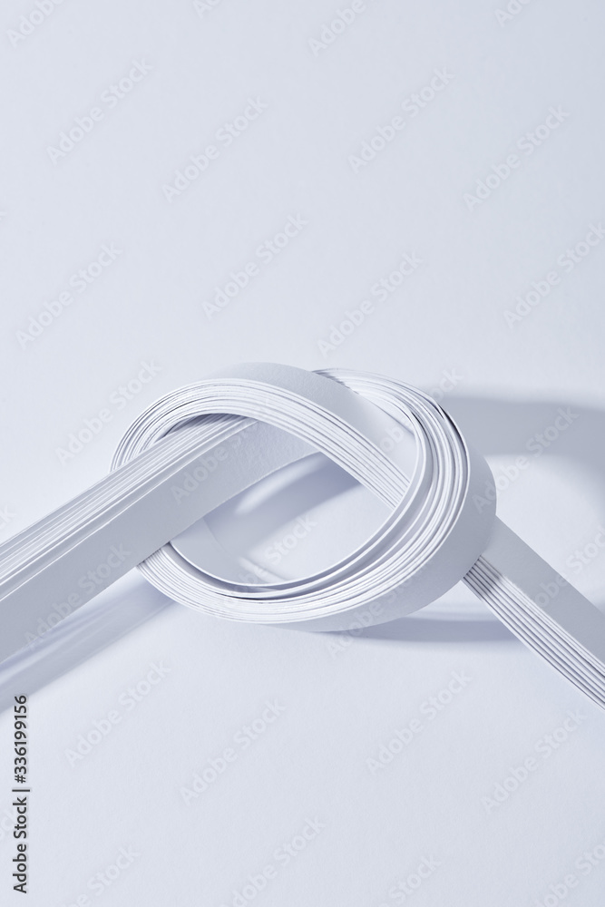 close up view of paper stripes in knot on white background